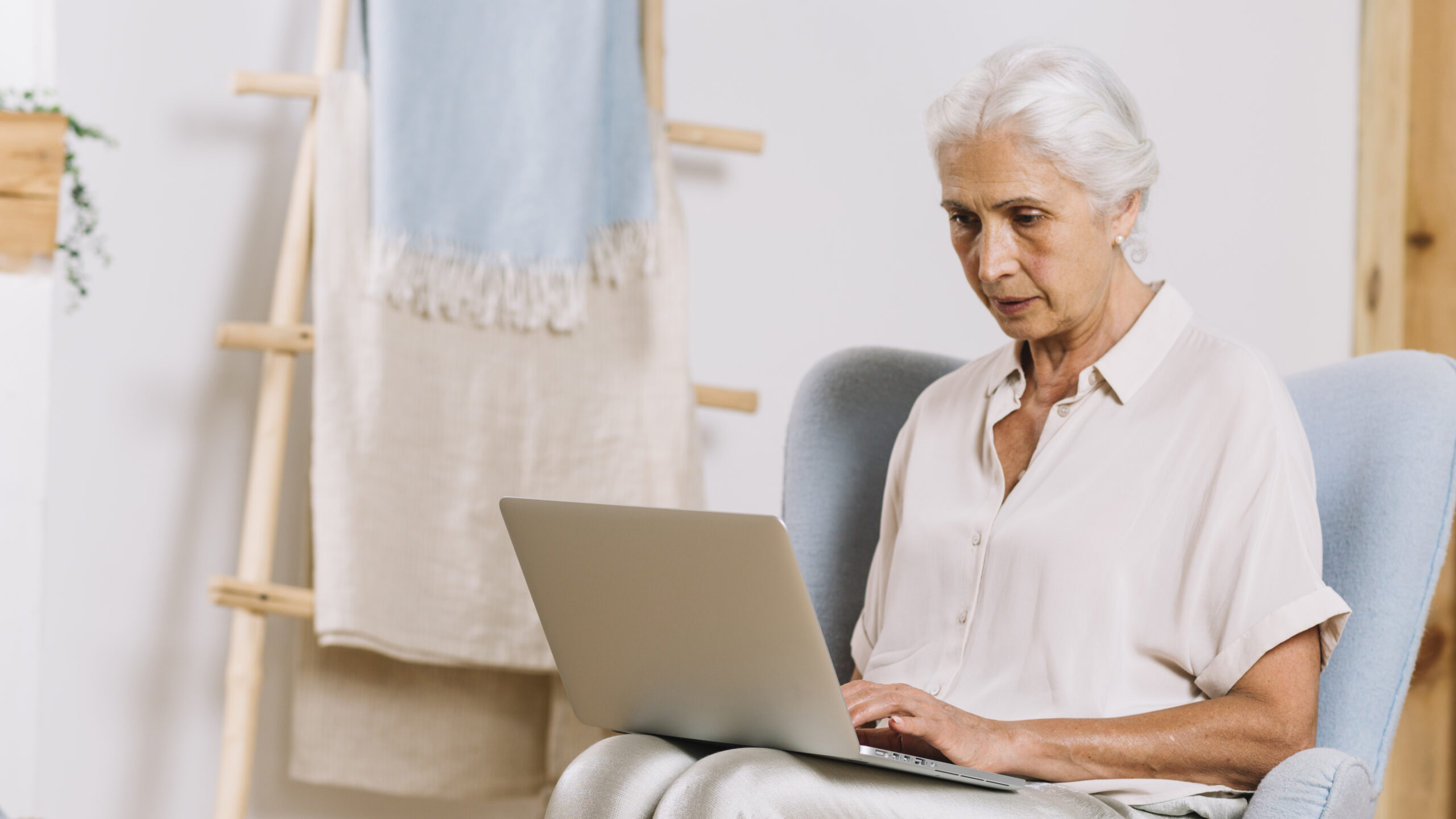 close up senior woman sitting in chair using laptop