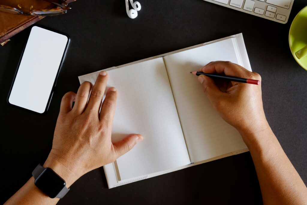 Person writing in an open notebook and making a plan to avoid a phantom-hacker scam.