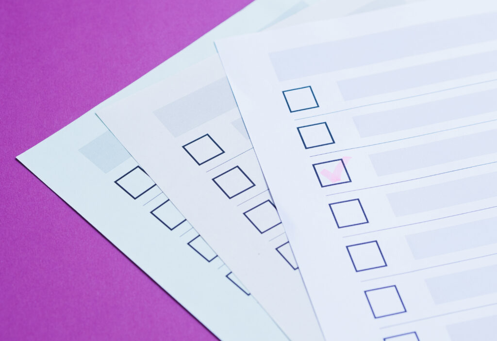 Stack of checklists with one box ticked on a purple background