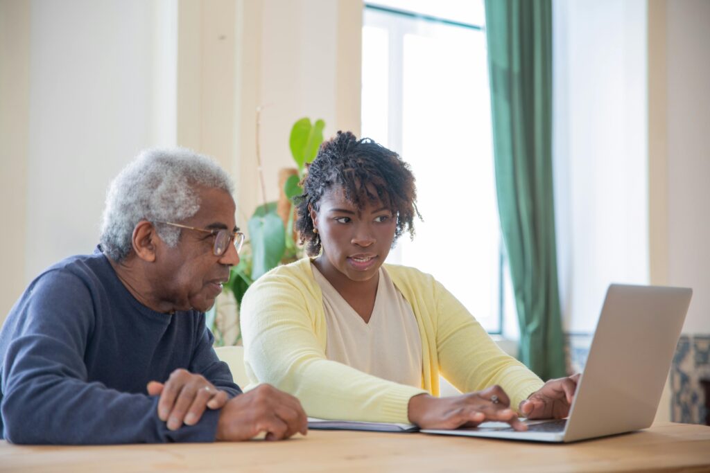 Adult woman calmly guiding her father on a laptop at home