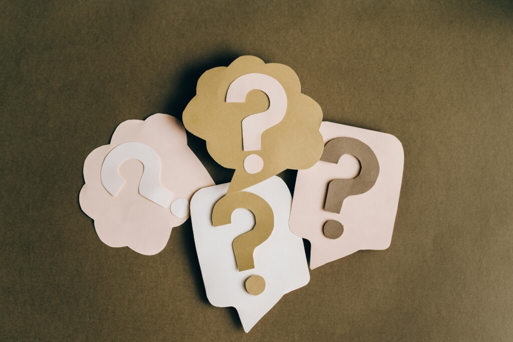 Paper cutouts of question marks on a brown background