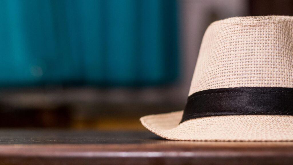 Light-colored straw hat with black ribbon on a wooden surface