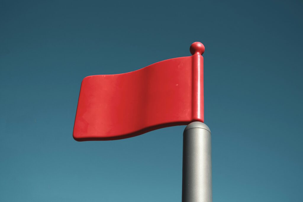 Red flag waving against a clear blue sky — showing “red flags” you should watch for in 2025.