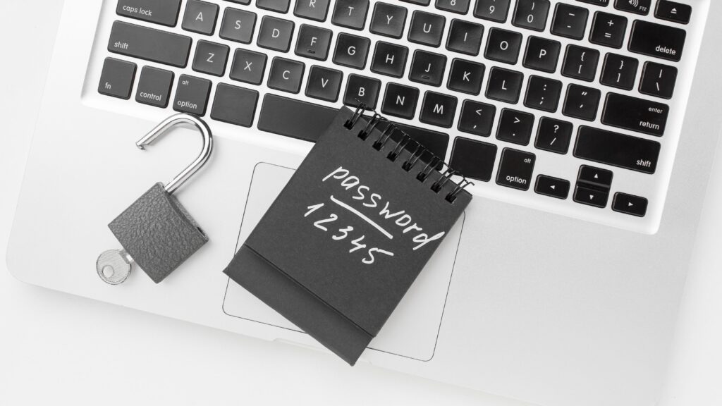 Open padlock and notepad with a simple password on a laptop, representing the risks of password reuse and data breaches.