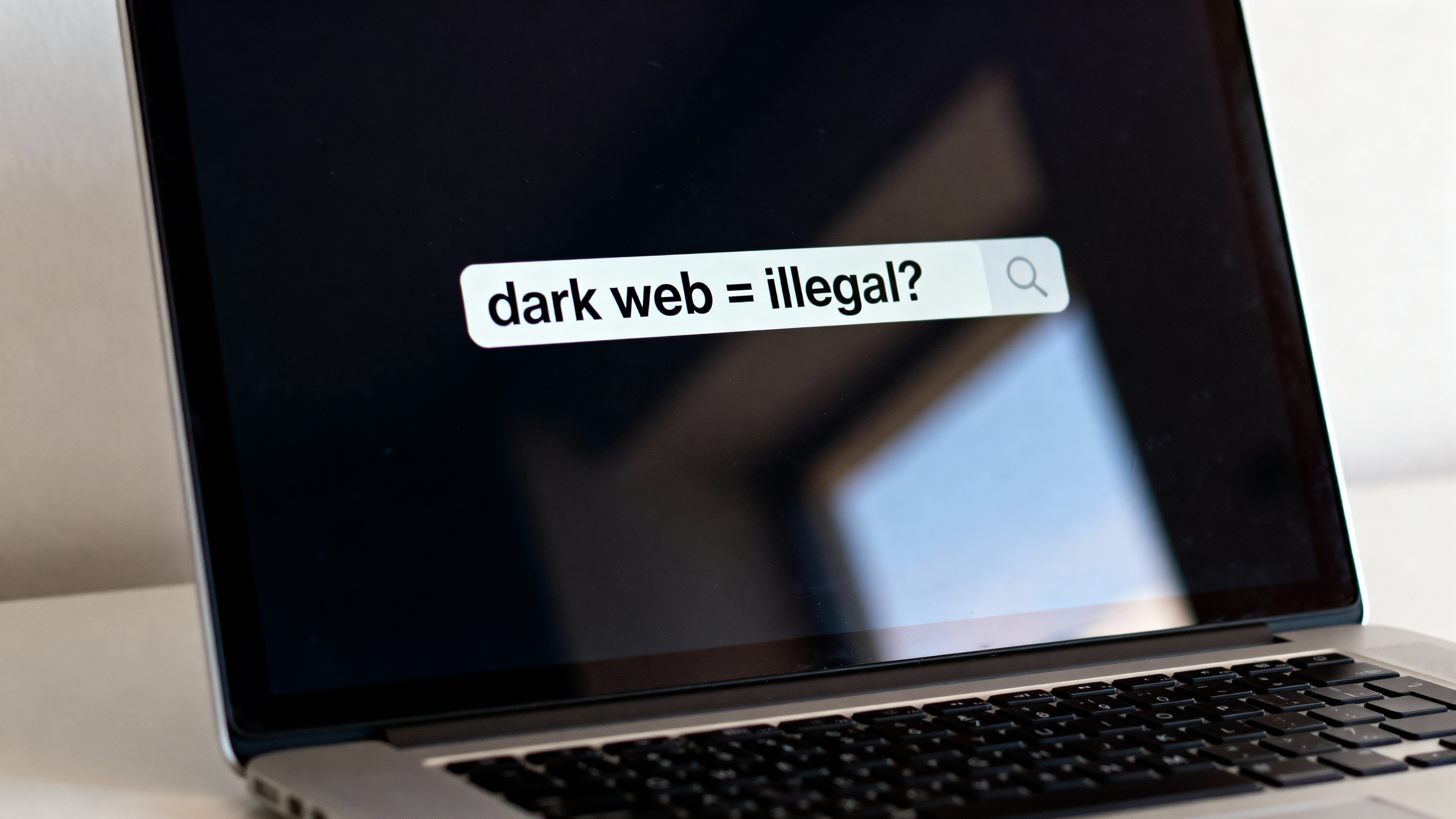 A laptop screen showing a search bar with the text “dark web = illegal?” highlighting confusion and common myths about the dark web.