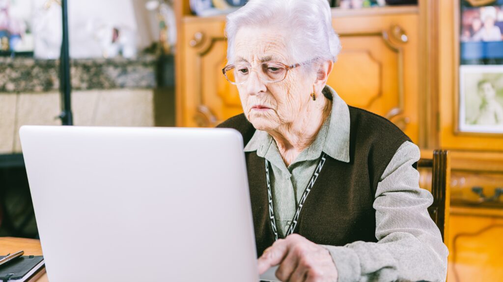 Senior woman using a laptop at home, highlighting how older adults are more vulnerable to hidden data collection and data brokers.