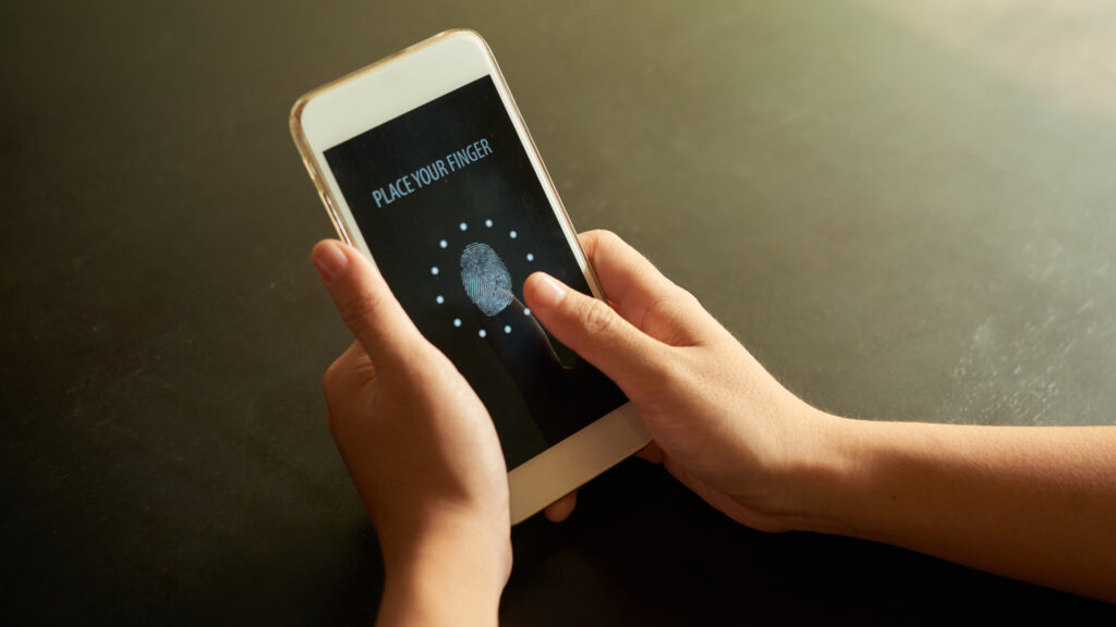 Hands using fingerprint authentication on a smartphone screen, showing biometric verification.