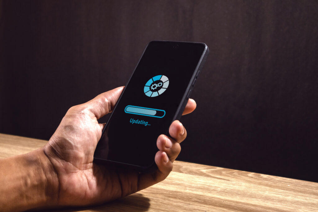 Hand holding a smartphone displaying a software update progress bar, representing device security and system updates.