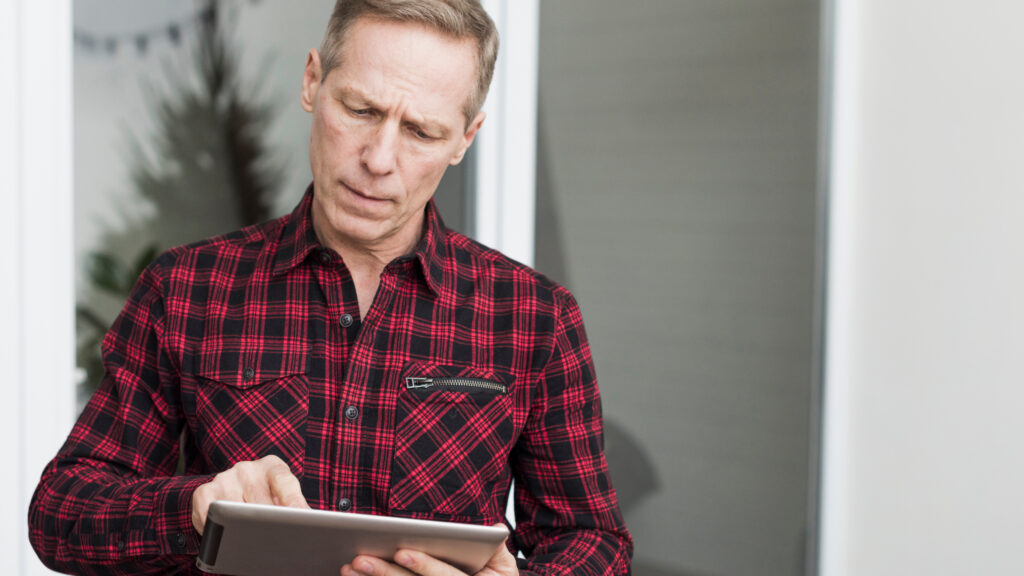 Medicare user reviewing information on a tablet after responding to a zero-cost back brace scam advertisement