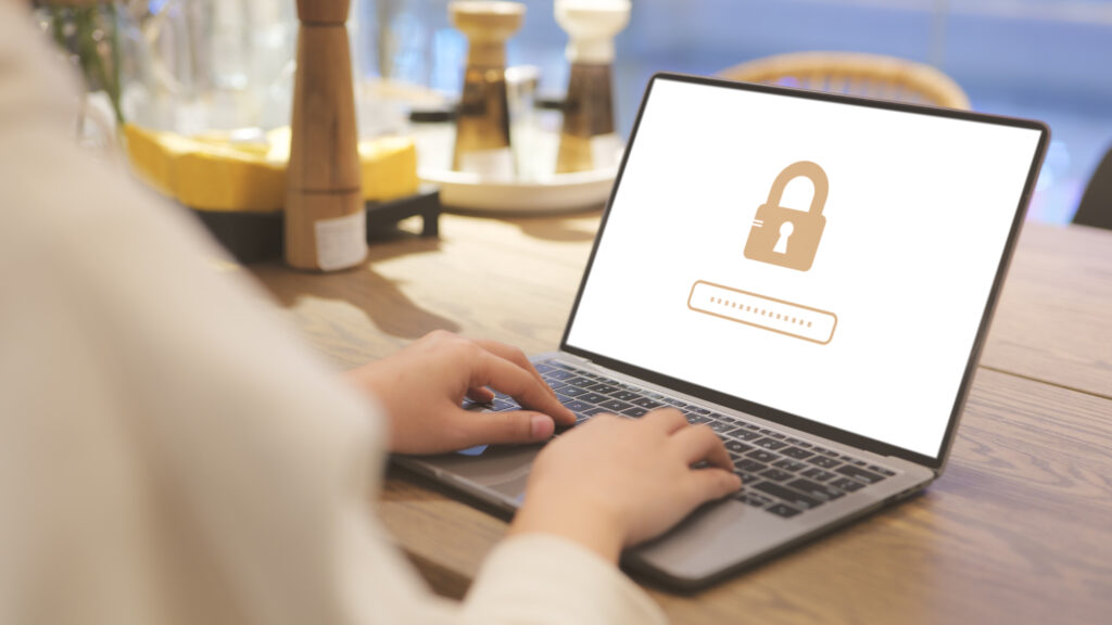 Person typing on a laptop displaying a lock icon and password field, representing email security and account protection.