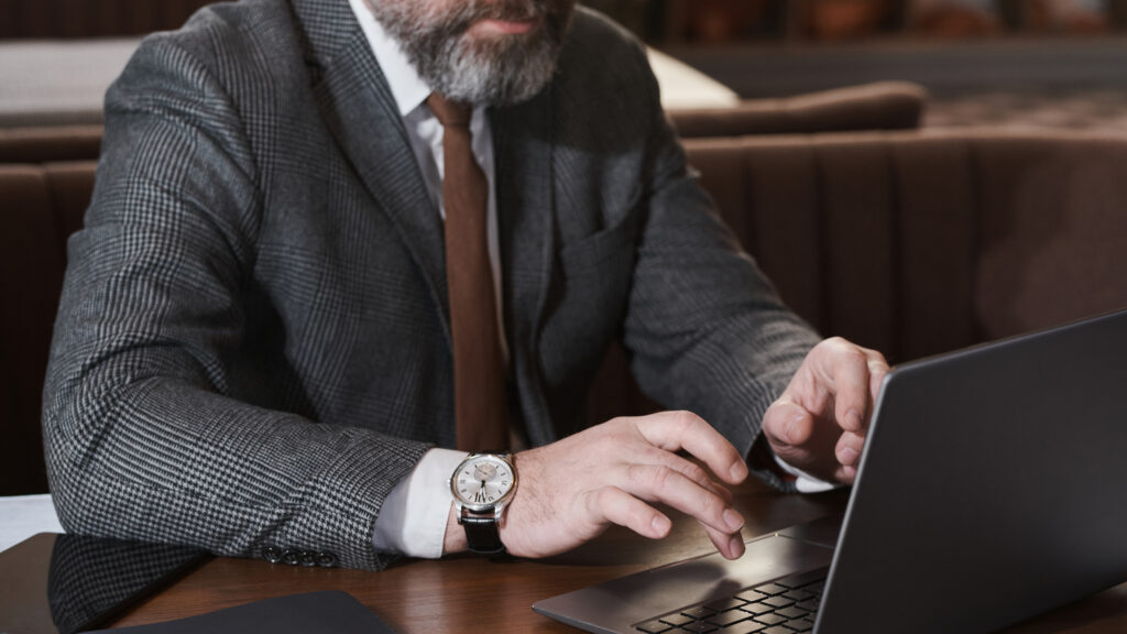 Man dressed like a lawyer using a laptop while posing as a legal professional in an online recovery scam