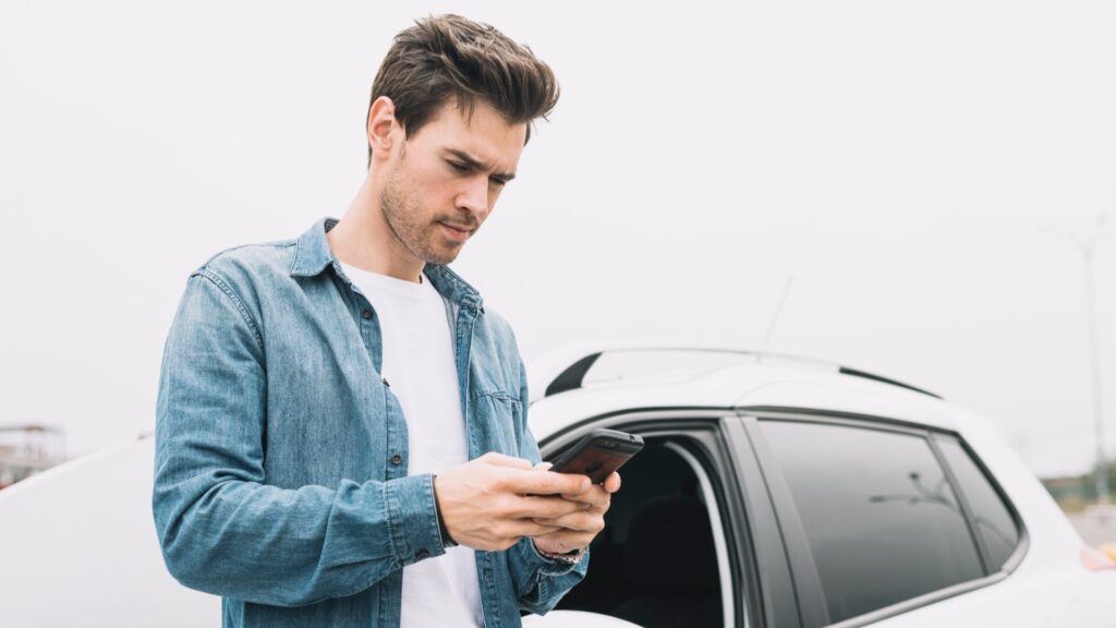 Driver checking a phone while standing next to a car before taking action