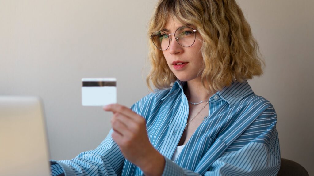 Woman holding a bank card while using a laptop for online banking
