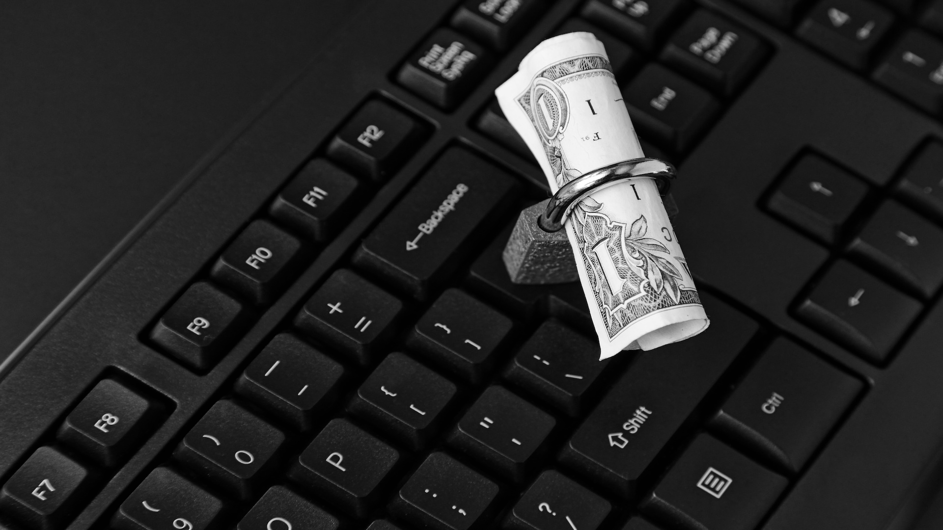 Padlock wrapped around a dollar bill on a laptop keyboard, representing money scams, online fraud, and the need to protect your finances in 2026.
