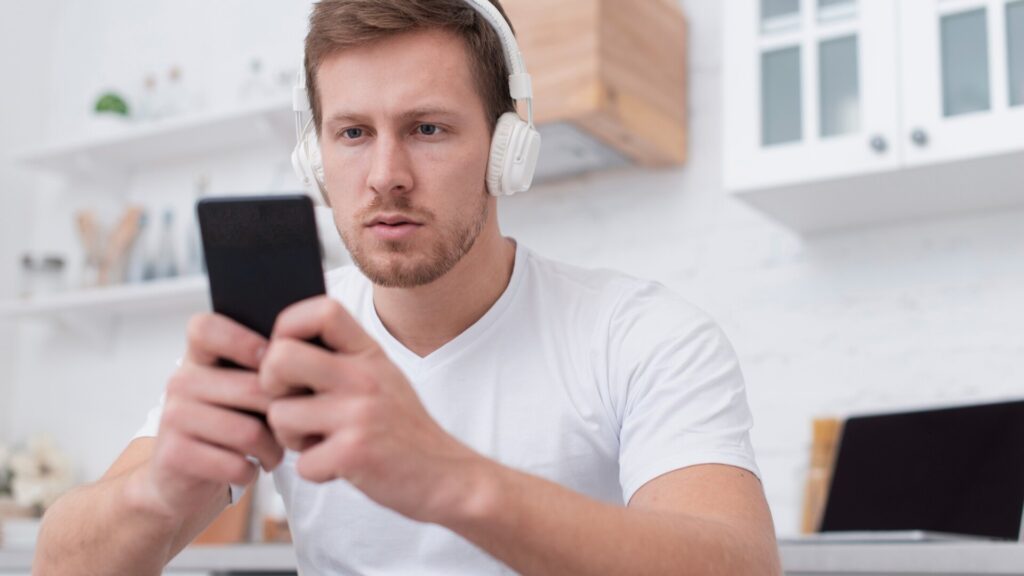 Man looking at his smartphone at home, checking apps and notifications
