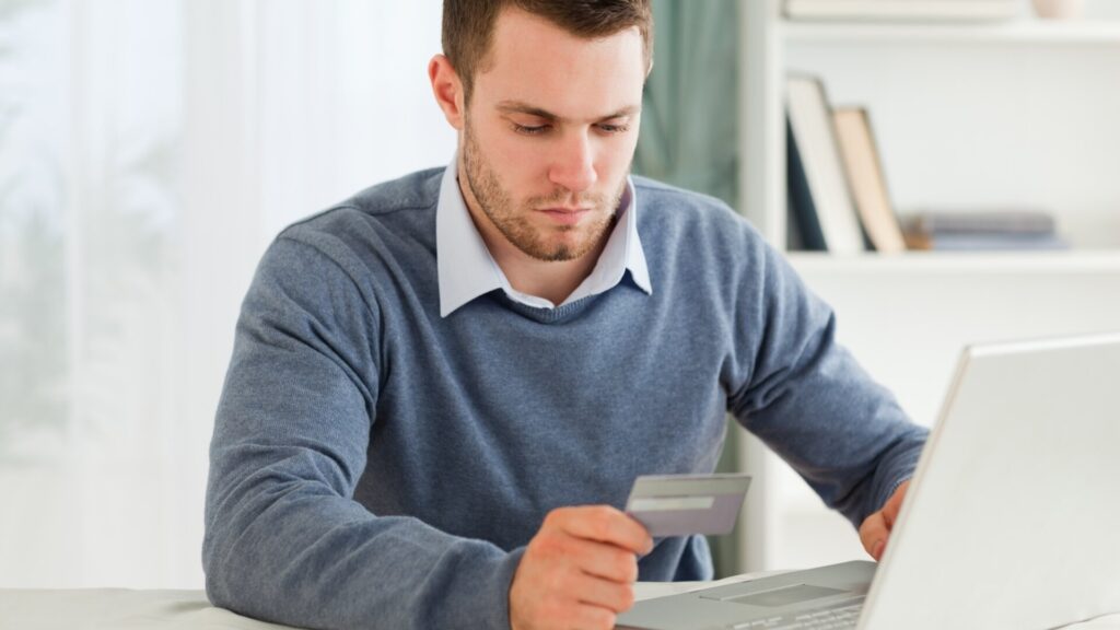 Man reviewing a payment card statement on a laptop to check for suspicious activity.