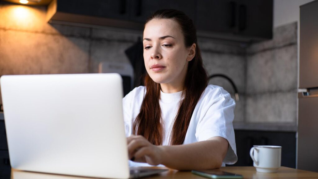 Woman using a laptop at home while reviewing information after a data breach notification.