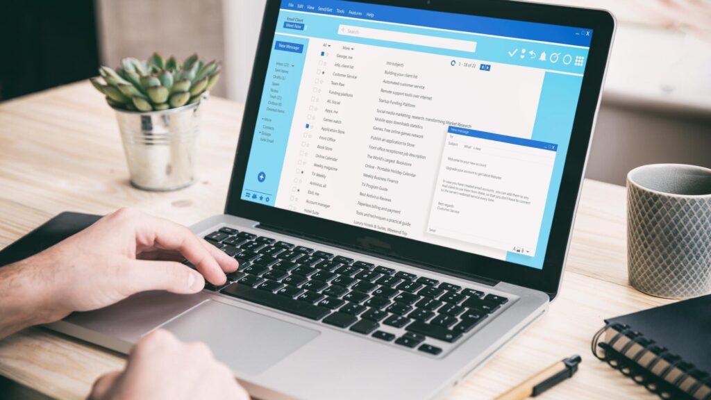 Person checking emails on a laptop while reviewing messages that could be part of a scam.