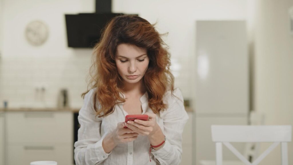 Woman looking at a message on her smartphone after learning about a passport data leak.
