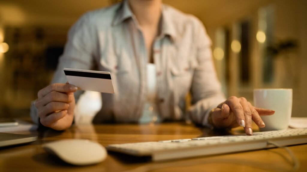 Person holding a credit card while using a computer to review accounts after a data breach.