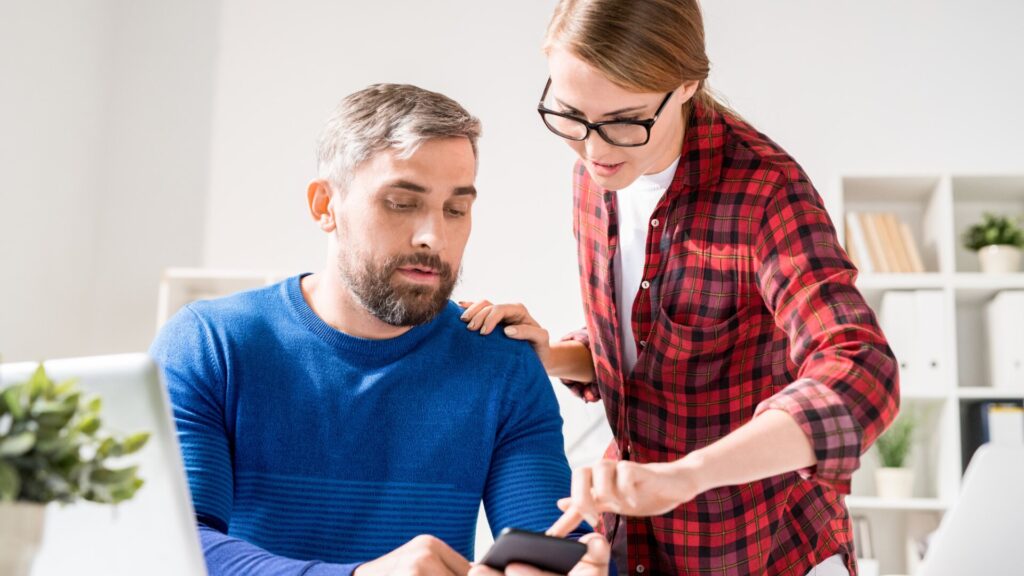 Two coworkers reviewing information together on a computer.