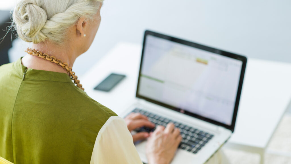 Older woman using a laptop at home after receiving a message about moving her pension to avoid inheritance tax