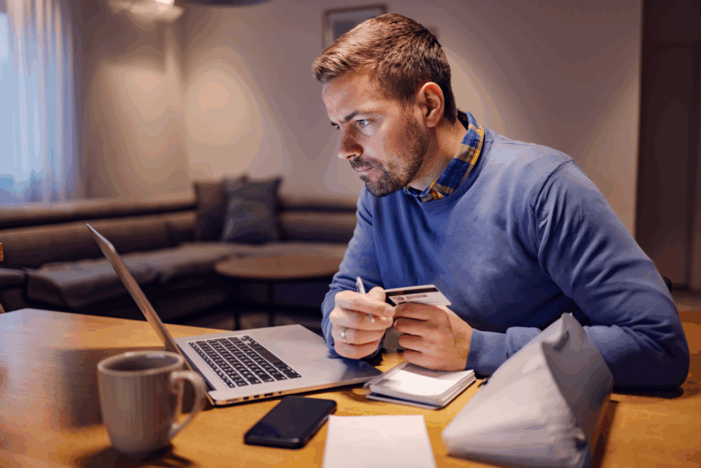 Man using a laptop and credit card at home, checking an online payment