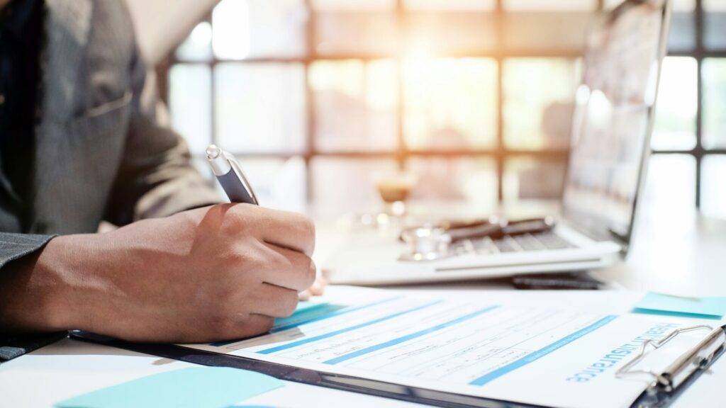 Person reviewing healthcare paperwork and records at a desk.