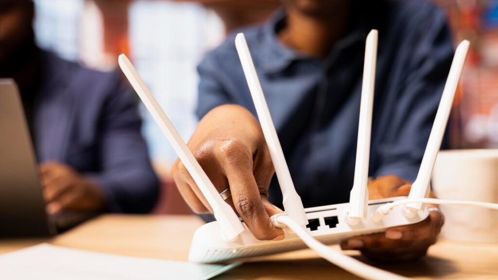 A person connects a Wi-Fi router, illustrating simple steps to update and secure a UniFi router or network device.