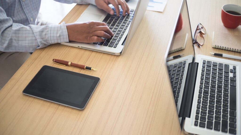 Employee uses a work laptop beside personal devices as a reminder to keep sensitive personal tasks off company computers.