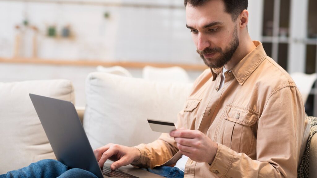 Man using a laptop and holding a credit card while reviewing his financial accounts after the TPWD data breach.