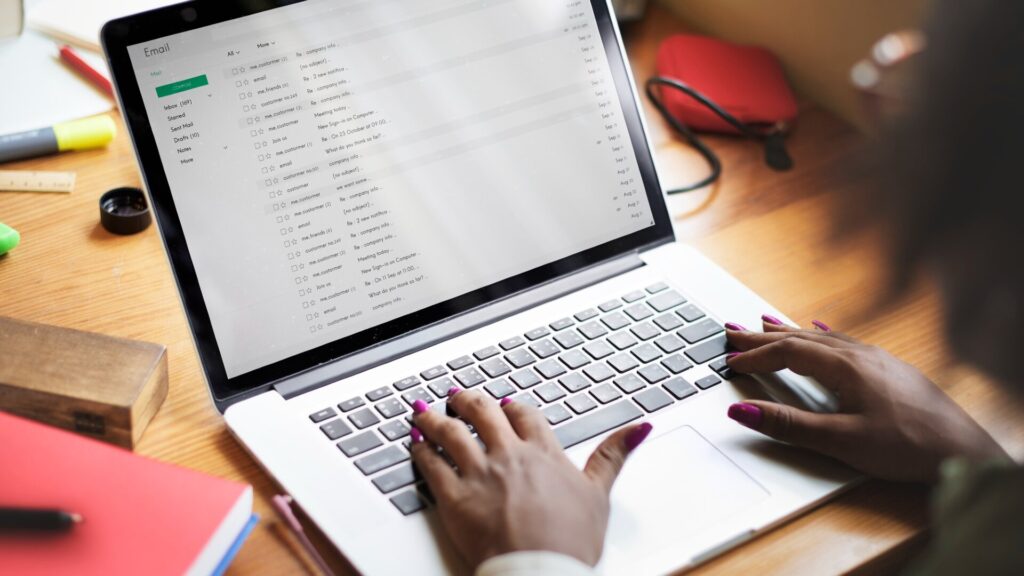 Person using a laptop to manage email messages, representing online account security and scam prevention.