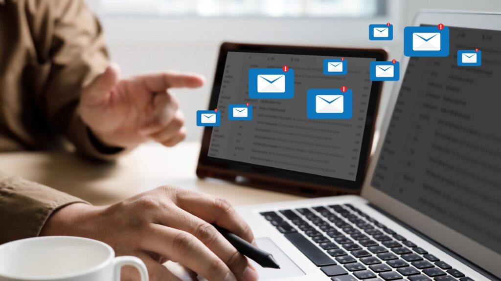 A person reviews multiple email alerts on a laptop, illustrating how criminals may use stolen personal information to create convincing phishing and impersonation messages.