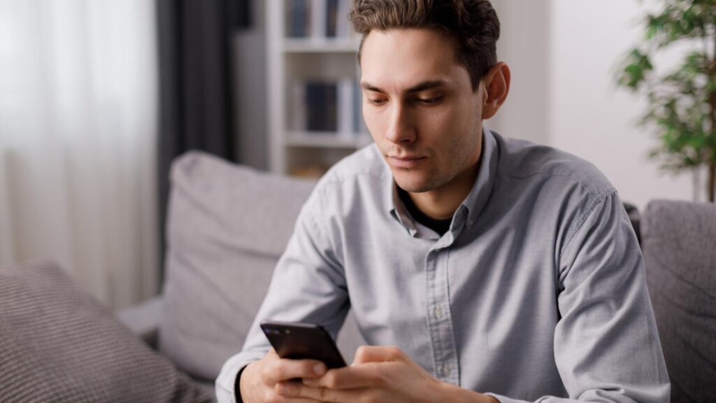 Person checking a smartphone message, illustrating how scammers contact pet owners after they post about missing animals online.