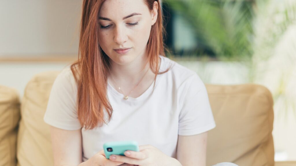 A woman checks her phone for suspicious messages after reports of confidential iPhone supplier information being leaked.