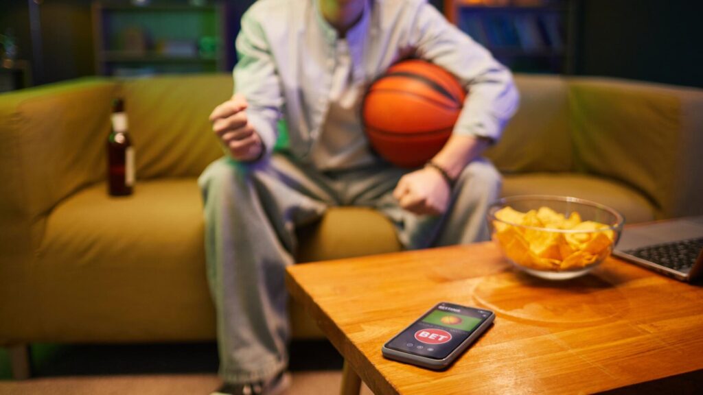 Basketball fan using a phone as the Madison Square Garden data breach raises risks of fake ticket, account, and payment scams