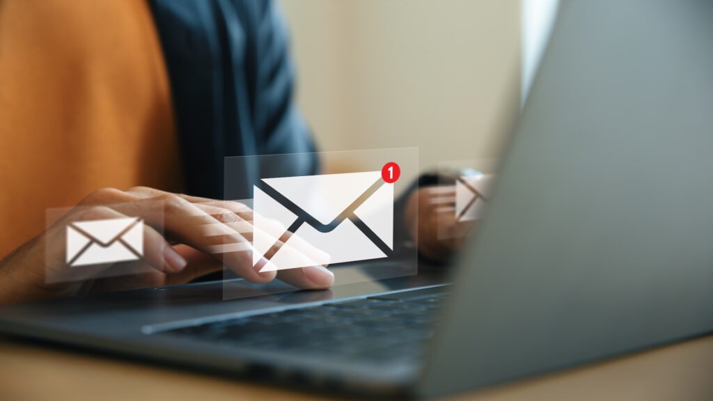 Person using a laptop with email notification icons, illustrating email exposure risks that anyone can face.