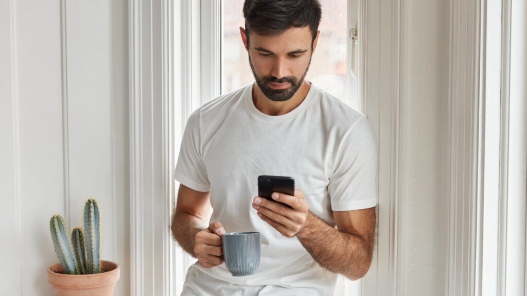 Man checking his smartphone before reviewing app location permissions and privacy settings on Android.