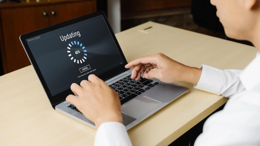 Person using a laptop during a software update, illustrating simple steps to download programs more safely.