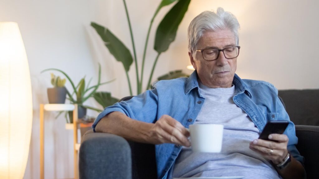 Older man reviewing his phone while taking steps to respond to identity theft and protect his financial accounts.